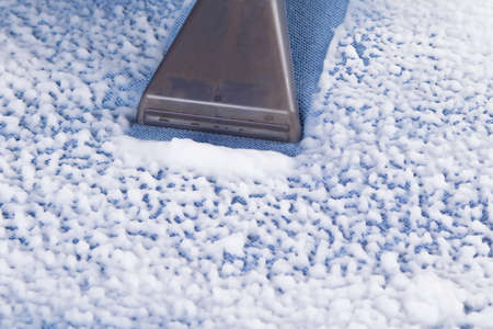 close-up of a washing vacuum cleaner picking up dirty foam from the fabric of the sofaの写真素材