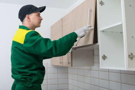 the master of furniture assembly, checks the correct installation of the door on the hanging cabinetの写真素材