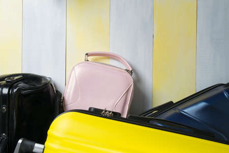 on a yellow-gray background, suitcases for traveling and a small purse, close-up, there is a place for the inscriptionの写真素材