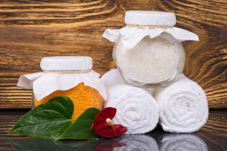 on a dark wooden background, a towel wrapped in a roll and bath salt in a glass jar, for relaxation, close-upの写真素材