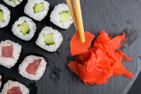 assorted salmon and cucumber rolls, on a black table and pickled gingerの写真素材