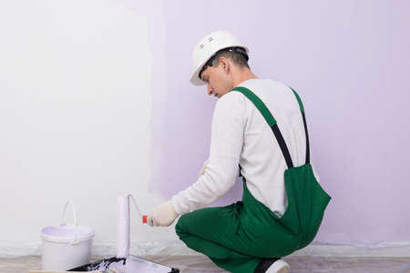 a man in overalls repaints the white walls in a different colorの写真素材