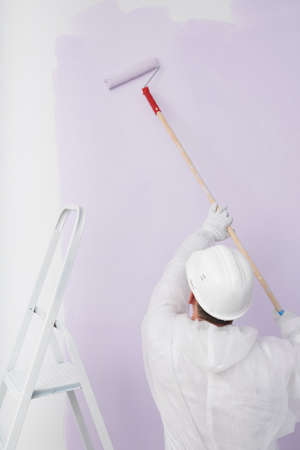 a worker in a helmet paints the wall purpleの写真素材