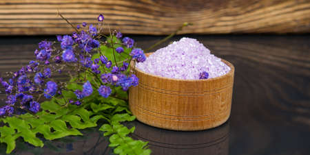 on a dark wooden background, purple bath salt, for relaxation, in a jar, with flowers for fragranceの写真素材