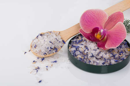 close-up, on a white background, bath salt for relaxation, on a wooden spoon and a plate with an orchidの写真素材