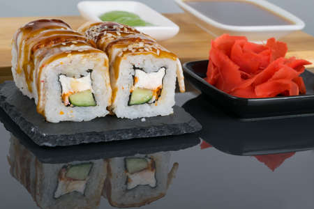 on a black table with a reflection, eel rolls and ginger flavor seasoning, close-upの写真素材