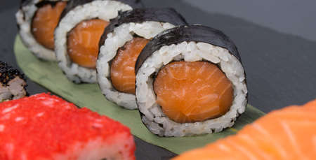 on a dark table, on a green bamboo leaf, Japanese salmon rolls, close-upの写真素材