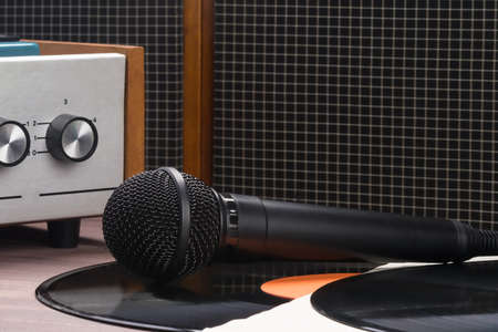 the microphone lies on a vinyl record in front of an old record playerの写真素材