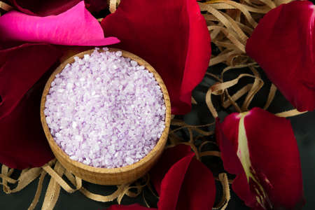 surrounded by red rose petals, crumbly lilac bath salt, in a wooden jar, for relaxationの写真素材