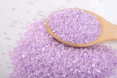 on a white background, on a wooden spoon, lilac bath salt was scattered, for relaxation, close-up