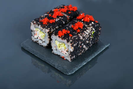 close-up, on a dark table with a reflection, Japanese rolls with shrimp, fresh salad and flying fish caviarの写真素材