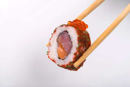 close-up, on a white background, wooden sticks hold a Japanese roll of tuna, pink salmon, red caviar and flying fishの写真素材