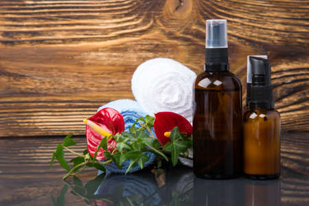 on a dark wooden background, items for spa treatments, a towel wrapped in a roll and aromatic oils for massageの写真素材