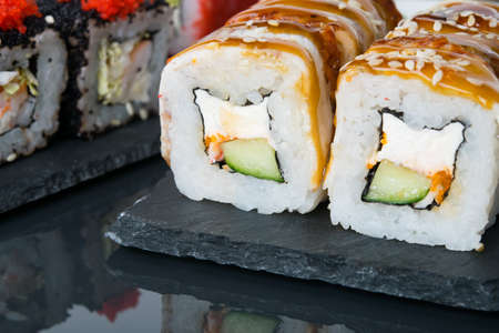 close-up, on a dark table with a reflection, Japanese rolls, with eel, cucumber and cream cheeseの写真素材