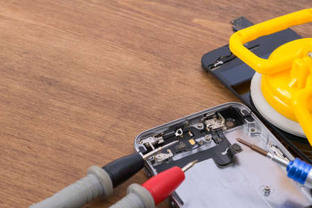 on a wooden table, close-up, troubleshooting using a smartphone tester to repair and replace the...