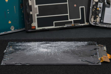 close-up of a broken smartphone screen on a black table in the process of repair, replacement parts...