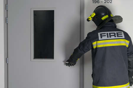 a fireman opens the front door in the entrance, rear view