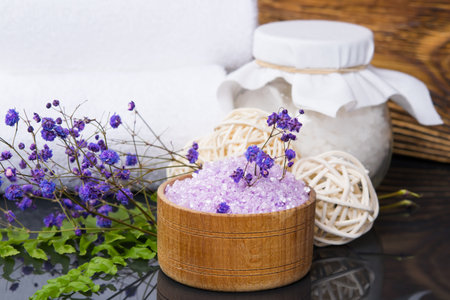 on a black table with reflection, bath salts, for relaxation, in jars, with flowers for fragrance, close-upの写真素材