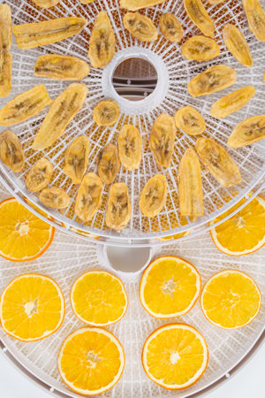 electric dryer for fruits and vegetables, close-up, bananas and oranges are laid out on a round grateの写真素材