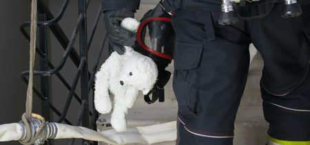 a firefighter stands on the stairs holding a teddy bear toy in his handの写真素材