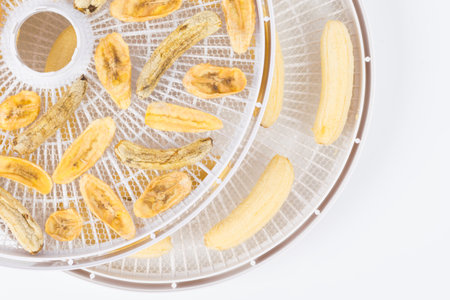 on a round white grill, dried sliced and whole peeled banana, close-upの写真素材