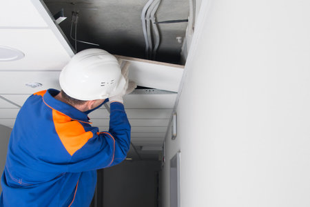 the master of installation of suspended ceilings, completes the assembly of plates on a metal frameの写真素材