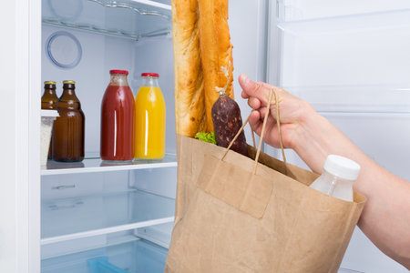 a man from the delivery service brought the purchased products and puts them in a white refrigerator, close-upの写真素材