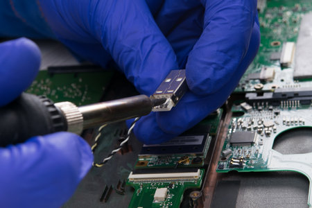 working hands in blue gloves, repairing the electrical circuit, soldered for charging, close-upの写真素材