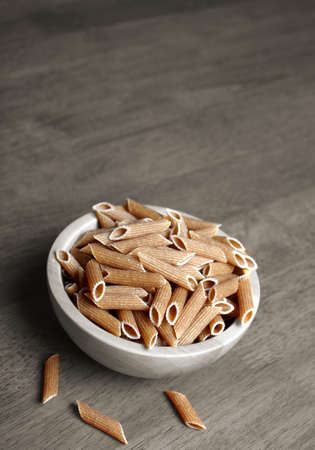 Uncooked organic whole wheat penne rigate on the table.の写真素材