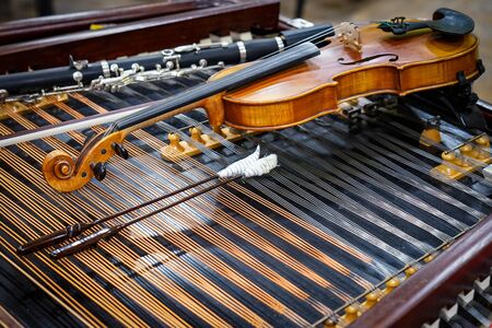 Antique violin and violin bow lying on dulcimer. Close up a violin instrument and cymbal before a concert. Music concept backgroundの写真素材