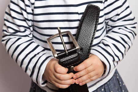 Stop child abuse. Small child's hands holding a belt.の写真素材