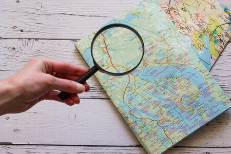Magnifying glass and ancient map. Hand holding magnifying glass over the map. Copyspace for text. Top view. Flatlay on wooden background.の写真素材