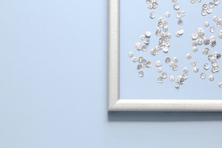 Part of the silver frame is decorated with confetti with space for text on blue background. Flat lay, top view. Minimal background.の写真素材