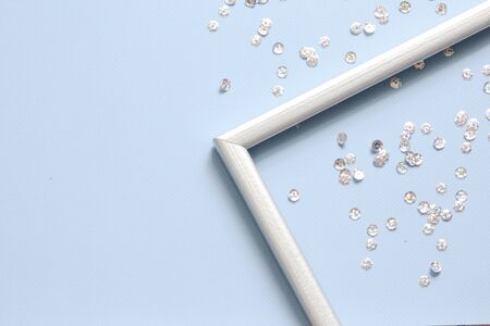 Part of the silver frame is decorated with confetti with space for text on blue background. Flat lay, top view. Minimal background.の写真素材