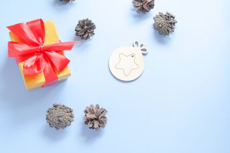 Pine cones near the box with a red bow on a blue background. Flat layの写真素材