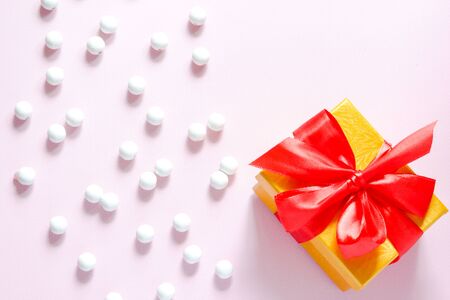 White wooden beads about with gift box on a pink background. Flat layの写真素材