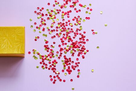Closed yellow gift box with party confetti on a pink background. Flat layの写真素材
