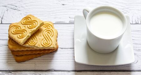 Cookies stacked and a cup of milk on a wooden background. Healthy snack.の写真素材