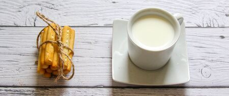 Cup of milk and breadstick on a wooden background. Healthy breakfast.の写真素材