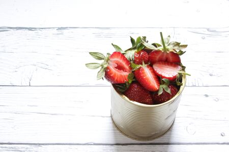 Red strawberries in a tin can on a white background. Healthy food.の写真素材