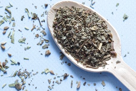Spoon of spice from herbs. Wooden spoon with spice albahaca on the blue backgroundの写真素材