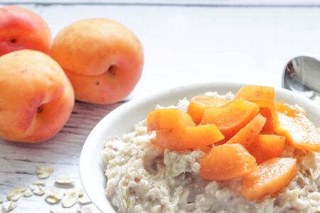 Oatmeal porridge with fresh apricots on a wooden background.の写真素材
