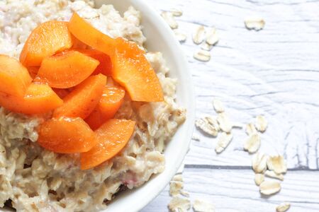 Oatmeal porridge with fresh apricots on a wooden background.の写真素材