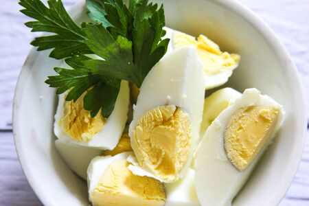 Boiled eggs, sliced isolated in the bowl. Halved eggs on wooden background.