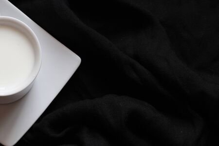 Home cozy composition. Cup of milk on black background. Fall background. Flat lay, top view, copy spaceの写真素材