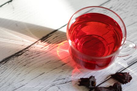 Red hot hibiscus tea in a glass mug on a wooden background. Red tea karkade. Healthy tea.の写真素材