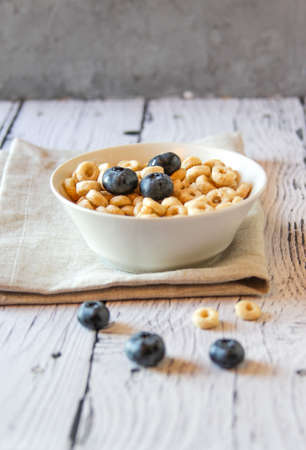 Honey rings with blueberries in a bowl on the table wooden background. Copy space. Horizontal...