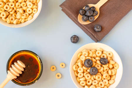 Honey rings with blueberries in a bowl on the table blue background. Copy space. Top view. Flat lay....