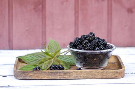 Fresh and sweet blackberry with leaves on the wooden background.