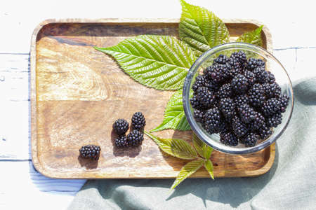 Fresh and sweet blackberry with leaves on the wooden background.